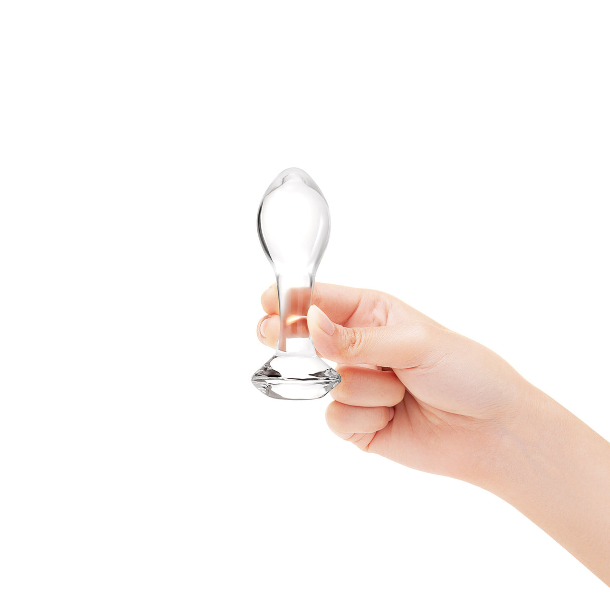 Hand holding a clear glass anal plug against a white background