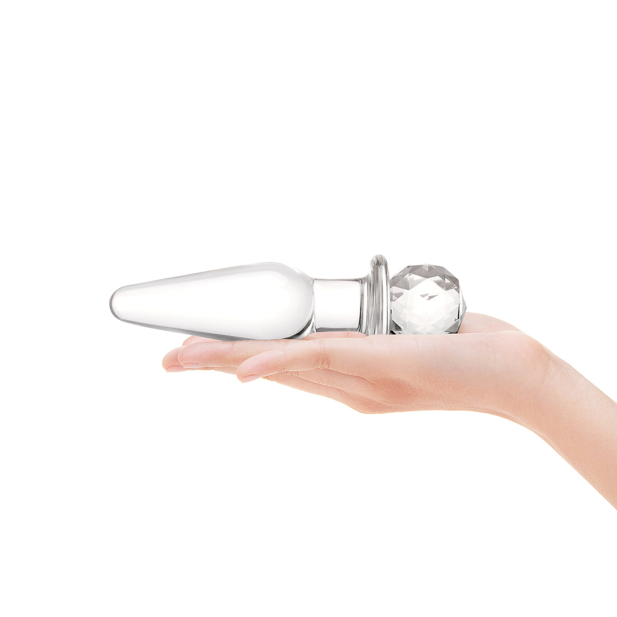 Clear Glass anal plug with round base held in a hand against a white background
