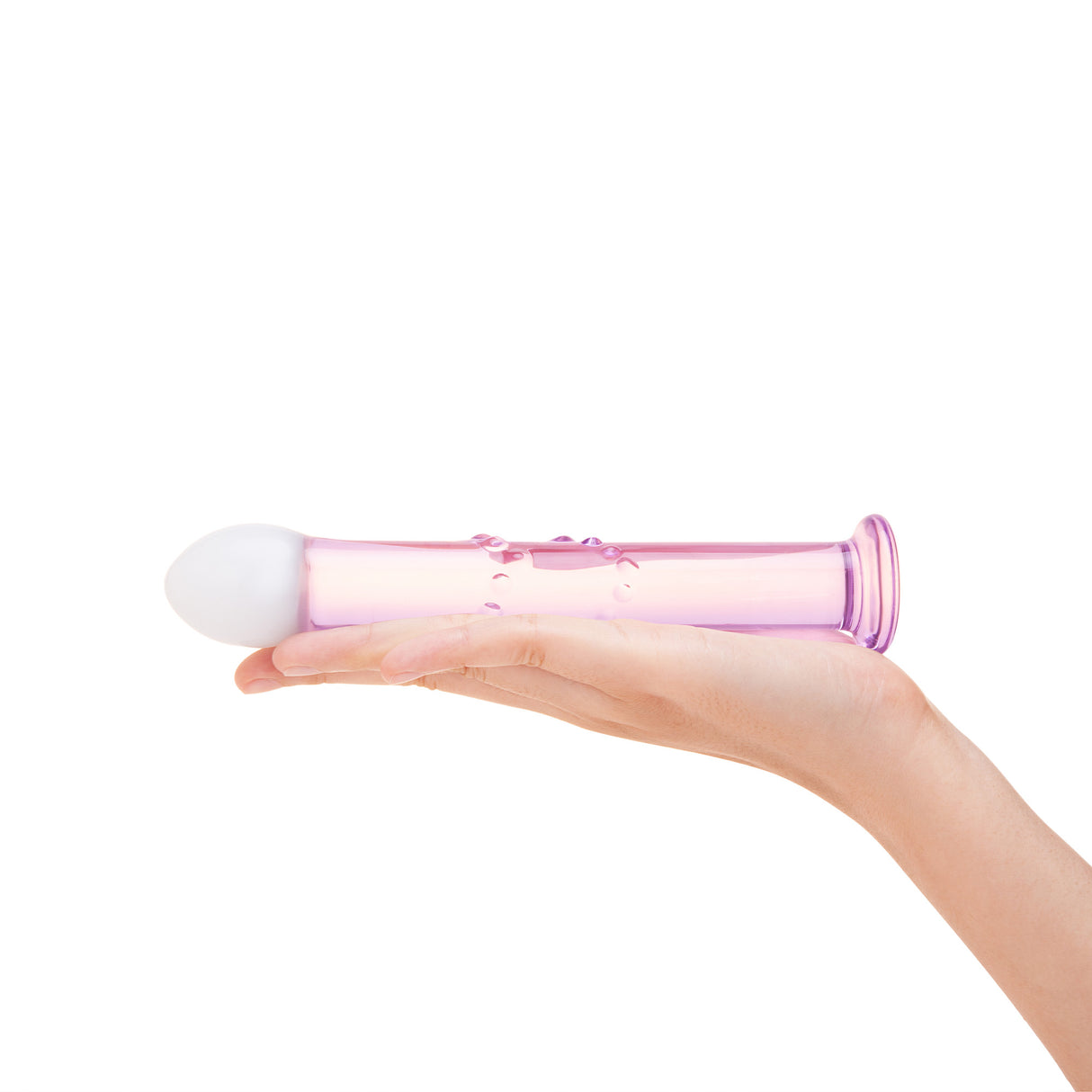 glass anal plug featuring a blush-pink shaft and frosted white tip with bubble-accented shaft held in a hand on a white background