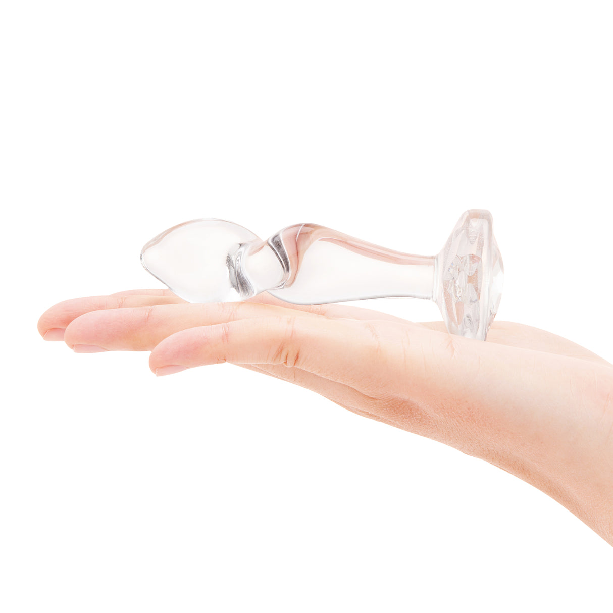 4" Sweet Twist Butt Plug - Large In-palm/Scale: Clear glass twist plug held in hand to demonstrate the contoured grip and overall size.