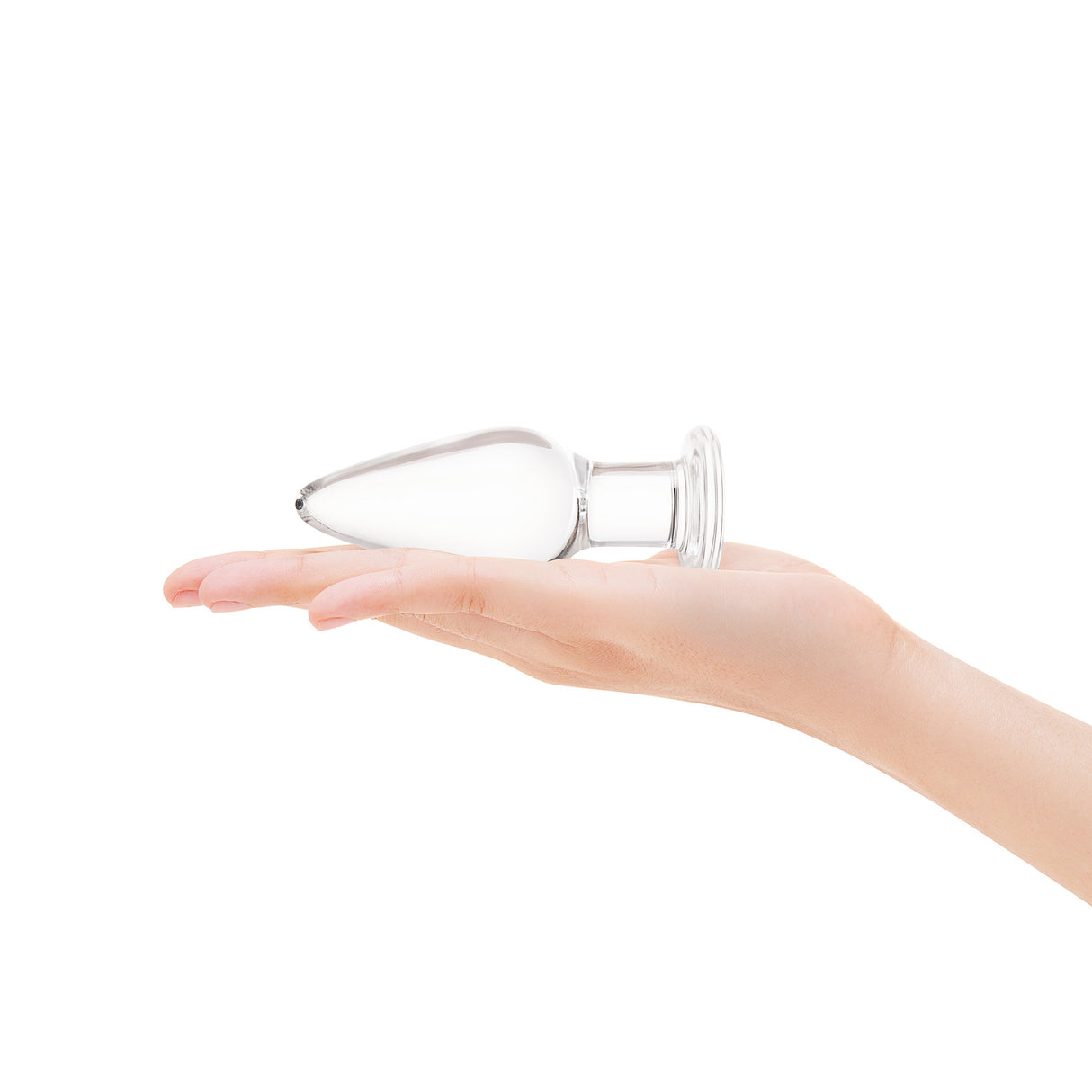 Clear glass anal plug with taoered tip and flared bottom held in a hand on a white background