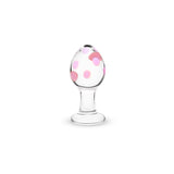 Glass anal plug with flat base with pink polka dots on a white background