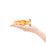 Hand holding a glass anal plug against a white background