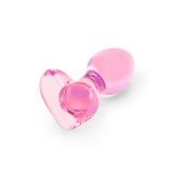 Pink heart-shaped glass anal plug on a white background