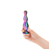 Hand holding a colorful, iridescent anal glass plug against a white background