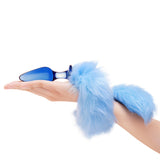 Blue Glass Plug with Fur Tail held by a hand on a white background
