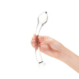 Clear glass dildo held by a hand on a white background