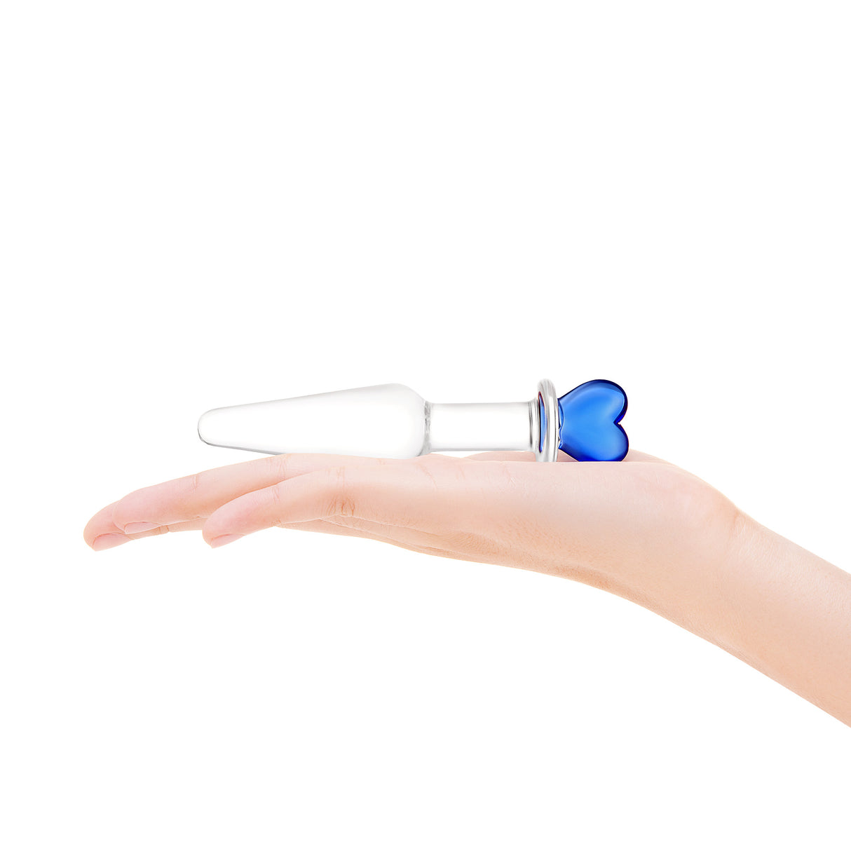 Hand holding a Clear glass butt plug with a blue heart-shaped base, slim neck and smooth tapered tip on a white background