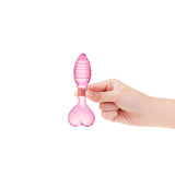 Pink Heart Base Ridged Plug featuring a tapered tip and ridget shaft held by a hand on a white background