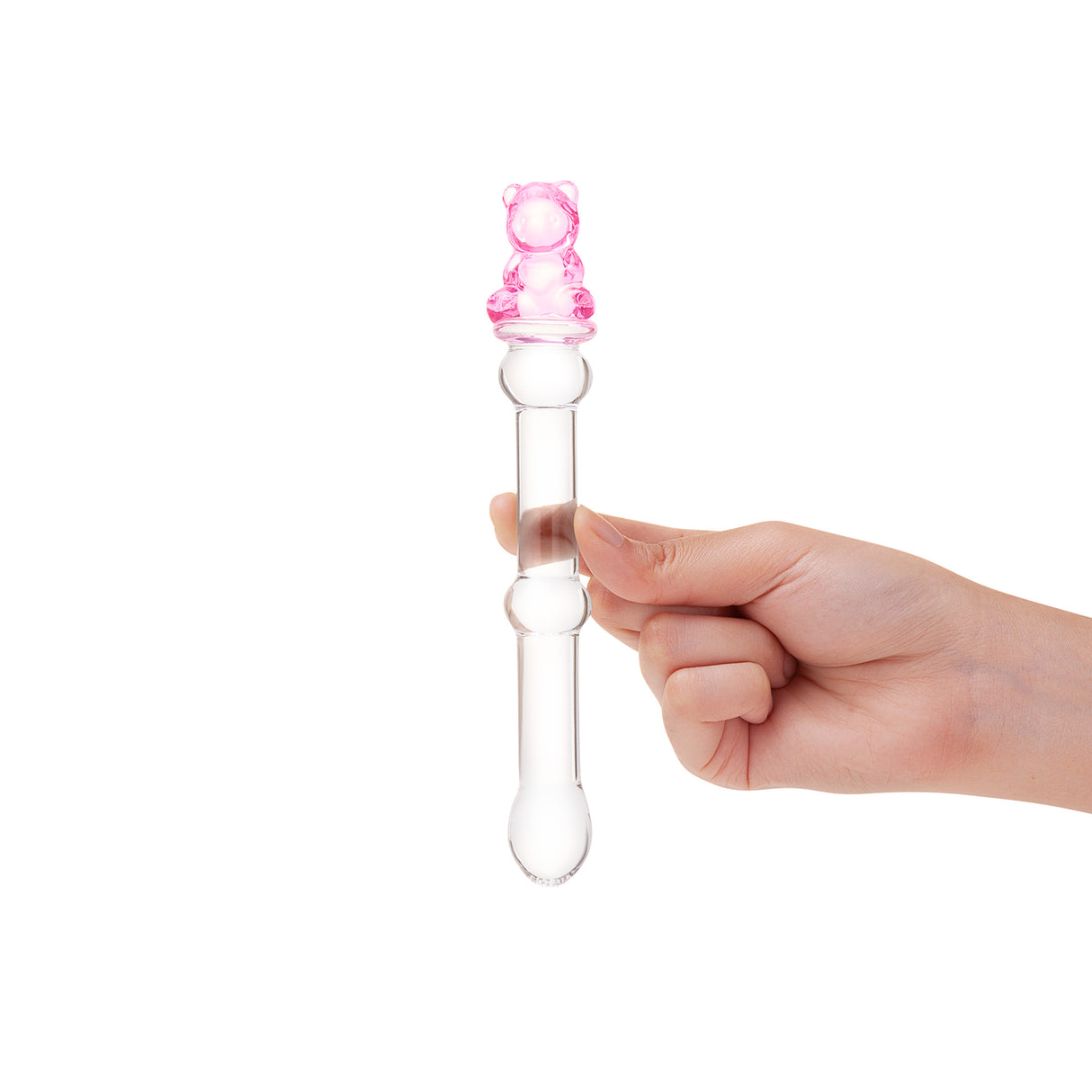 Hand holding a Clear beaded glass dildo featuing a tapered tip and cute pink bear base against a white background