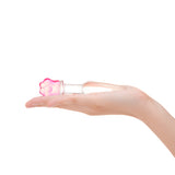 Hand holding a sGlass anal plug with slim shaft, tapered tip, and a secure pink flower base on a white background