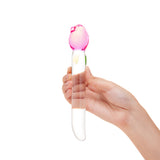 Hand holding a glass floral dildo—sleek shaft, tapered tip, and a secure pink tulip base on a white background
