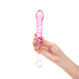 Hand holding a dual-ended glass dildo featuring a smooth end and a pink ribbed textured end against a white background