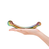Hand holding a Iridescent curved glass dildo featuring bulb ends and smooth shaft a white background