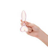 Hand holding a Ribbed Shaft Glass Anal Plug with a heart shaped base on a white background
