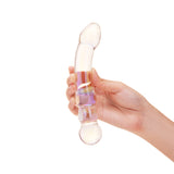 Hand holding a dual-ended glass dildo with teardrop and beaded ends on a white background