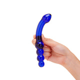 Hand holding a blue dual-ended glass curved dildo with graduated beads and tapered tip against a white background