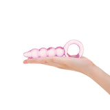 Pink glass anal plug with beaded shaft, tapered tip and ring base held in a hand on a white background