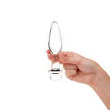 Hand holding a Sparkle Glass Anal Plug with tapered tip and flat, flared base against a white background