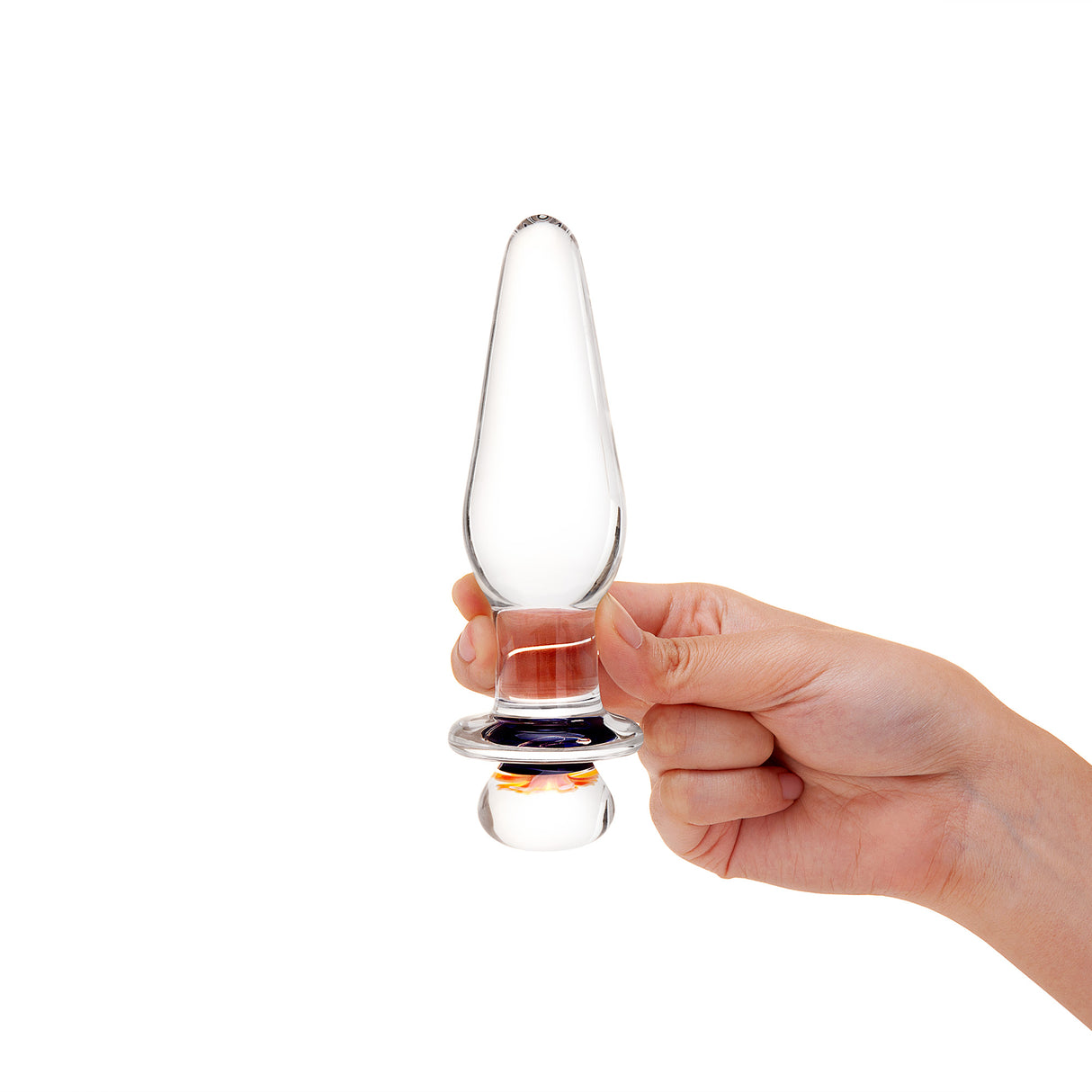 Hand holding a Glass anal plug with slim tapered tip and flower design on the base against a white background
