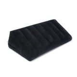 Black flocked b-Vibe Essentials inflatable sex position ramp fully inflated on a bed.