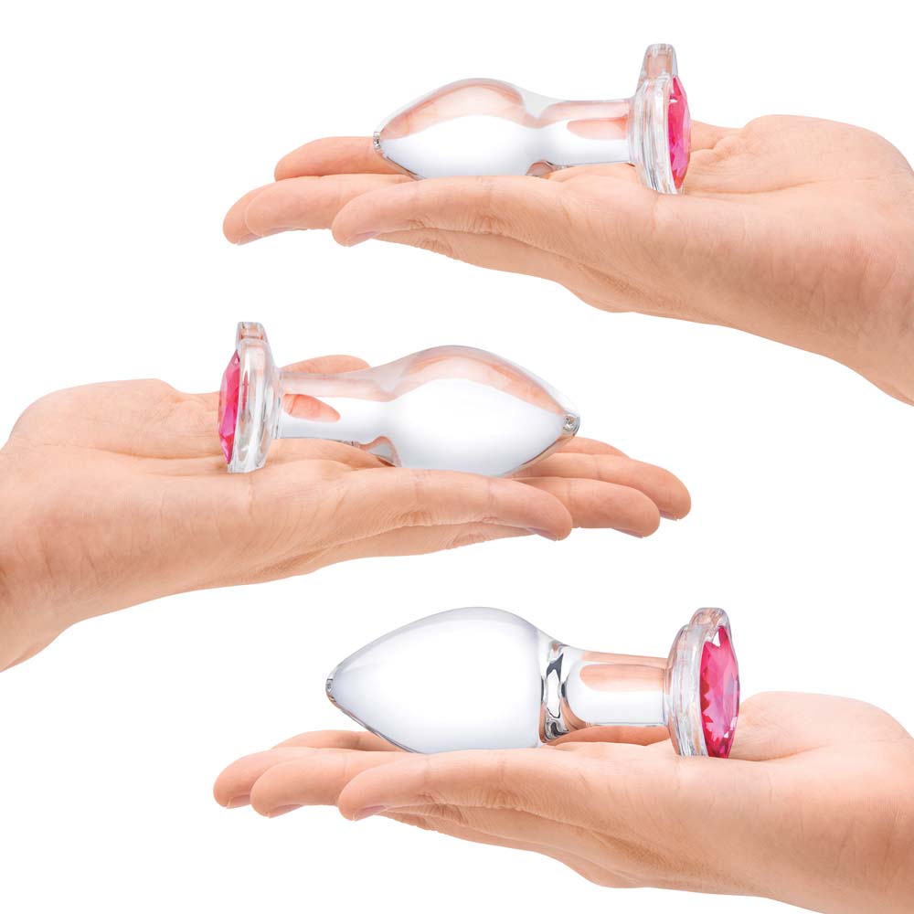 Model holding the small, medium and large size Anal Plugs as part of the 3 Piece Gläs Heart Jewel Glass Anal Training Kit
